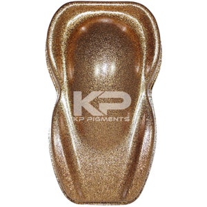 May include: A close-up of a gold glitter paint sample. The paint is a fine glitter with a metallic sheen. The sample is in the shape of a car hood.