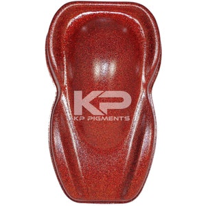 May include: A red glitter paint sample with a textured finish. The sample is shaped like a car hood and has the text "KP Pigments" printed on it.