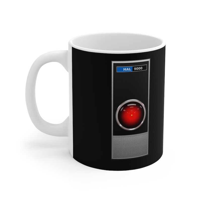 May include: White ceramic mug with a black design featuring a red button with the text "HAL 9000" above it.