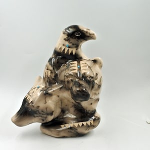 May include: A ceramic sculpture of three animals, a bird and two wolves, with intricate black and white patterns and turquoise accents.