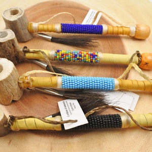 May include: Four traditional Native American pipes made of antler and wood with colorful beaded designs. The pipes are decorated with blue, turquoise, black, and multi-colored beads.