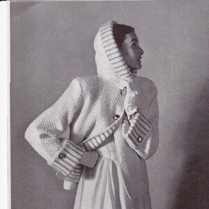 May include: A white knitted hooded jacket with a long white skirt. The jacket has a striped trim and buttons down the front.