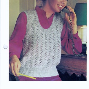 Könnte beinhalten: Ein grauer ärmelloser Spitzenpullover mit einem Chevron-Muster. Der Pullover wird von einer Person mit einem rosa Hemd darunter getragen. Das Bild stammt aus einem Strickmusterbuch.