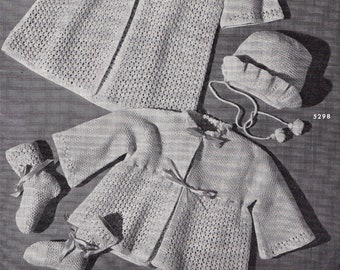 May include: A monochrome image showcasing knitted baby outfits. The sets comprise coats, hats, and booties, each embellished with ribbon ties. The text "ALL DRESSED UP AND Going Places" is displayed at the top of the image.