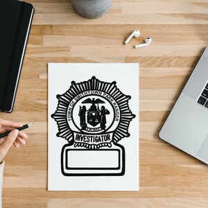 Puede incluir: Ilustración en blanco y negro de una insignia con el texto "Town of Smithtown Park Ranger Investigator" en una hoja de papel blanca.