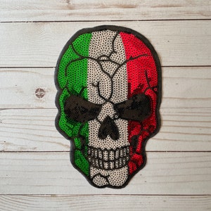 Puede incluir: Un parche con forma de calavera con un diseño de lentejuelas en los colores de la bandera italiana: verde, blanco y rojo.