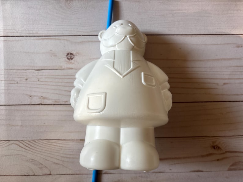 Peut inclure: Figurines en plastique blanc repr&eacute;sentant une personne avec une moustache et un design simple. La figurine est une tasse avec un trou pour paille en haut.