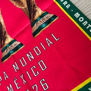May include: A red fabric with the text "COPA MUNDIAL M&Eacute;XICO 1986" in white. The image features the FIFA World Cup trophy in gold and green. A green and yellow border with white text is visible.