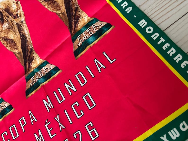 May include: A red fabric with the text "COPA MUNDIAL M&Eacute;XICO 1986" in white. The image features the FIFA World Cup trophy in gold and green. A green and yellow border with white text is visible.
