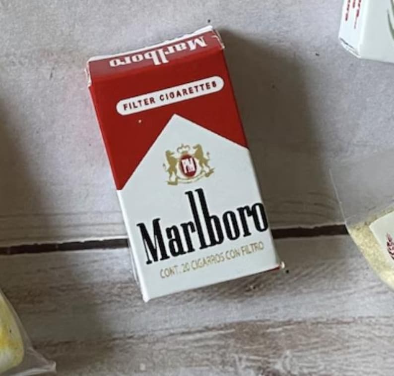 May include: A pack of Marlboro Filter Cigarettes. The pack is red and white with the Marlboro logo in black. The text "FILTER CIGARETTES" is printed on the top of the pack.
