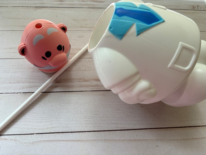 Peut inclure: Une figurine en c&eacute;ramique rose et blanche avec un trou en haut, une paille blanche et une figurine en c&eacute;ramique blanche avec un motif de cravate bleue.