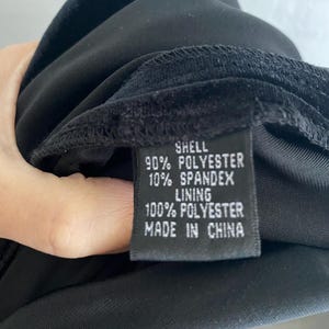 Puede incluir: Vestido de terciopelo negro con una etiqueta negra que dice "Shell 90% Polyester 10% Spandex Lining 100% Polyester Made in China"