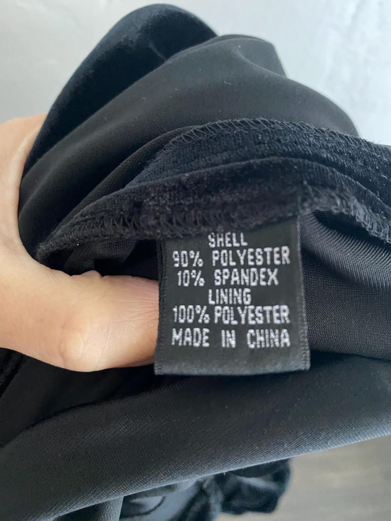 Puede incluir: Vestido de terciopelo negro con una etiqueta negra que dice "Shell 90% Polyester 10% Spandex Lining 100% Polyester Made in China"