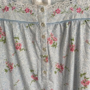 May include: Light blue paisley print nightgown with pink floral embroidery and lace trim. The nightgown has a button-down front and a scoop neckline. The label reads "Secret Treasures Sleepwear".