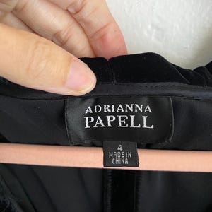 Puede incluir: Vestido de terciopelo negro con una etiqueta que dice "Adrianna Papell" y "4 Made in China".