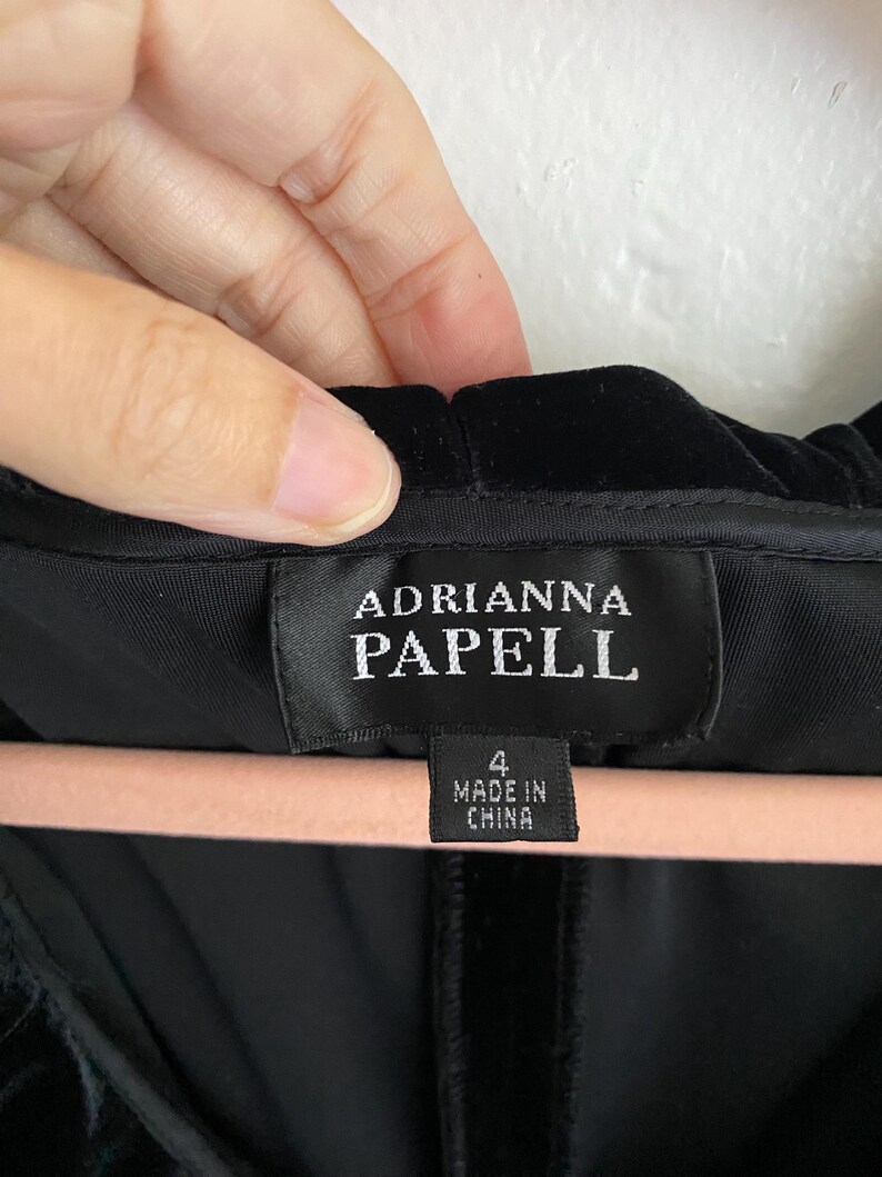 Puede incluir: Vestido de terciopelo negro con una etiqueta que dice "Adrianna Papell" y "4 Made in China".