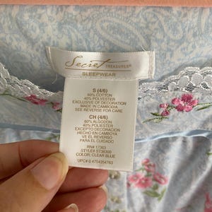May include: A light blue floral print sleepwear garment with a lace trim. The tag reads "Secret Treasures Sleepwear" and includes size, material, and care instructions. The garment is made of 60% cotton and 40% polyester.