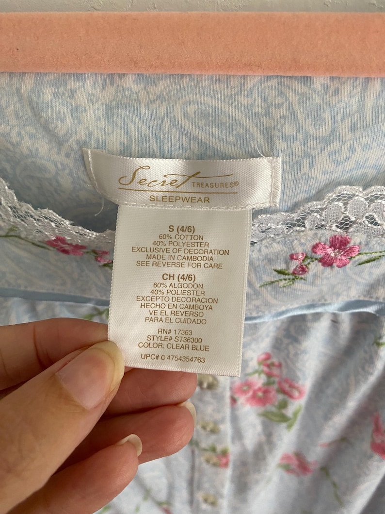 May include: A light blue floral print sleepwear garment with a lace trim. The tag reads "Secret Treasures Sleepwear" and includes size, material, and care instructions. The garment is made of 60% cotton and 40% polyester.