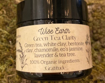 Può includere: Un barattolo in vetro ambrato scuro con coperchio nero ed etichetta beige. Il testo recita: Wise Earth, Green Tea Clarity, Green tea, white clay, bentonite clay, chamomile, eo's jasmine, lavender & tea tree. 100% Organic ingredients. ..Gratitude..