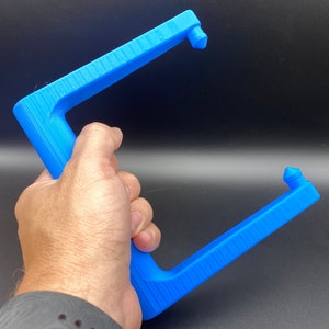 May include: A blue plastic tool with two pointed ends, designed for gripping and pulling objects. The tool is held in a person's hand.