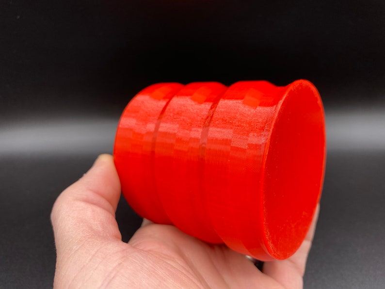 May include: A bright red, cylindrical container with a smooth, glossy finish. The container has three distinct bands around its circumference.