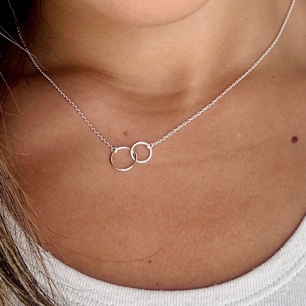 May include: A silver necklace with two interlocking circles as a pendant.