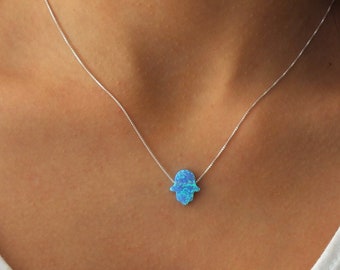 Peut inclure: Un collier en chaîne argent avec un pendentif main de Hamsa en opale bleue.