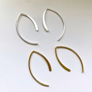 May include: Two pairs of minimalist earrings, one pair in silver and one pair in gold. The earrings are simple, thin, and curved.