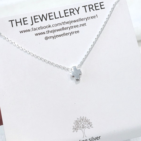 May include: A silver necklace with a small cross pendant. The necklace is on a white card with the text "THE JEWELLERY TREE" and website information.