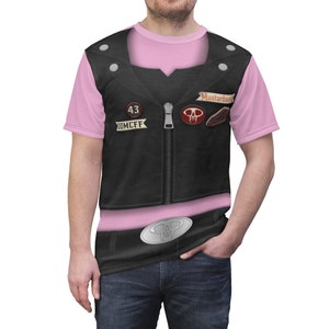 Può includere: Una t-shirt rosa con un giubbotto di pelle nero stampato su di essa. Il giubbotto ha una cerniera, una toppa con un teschio, una toppa che dice "Mustardseed" e una toppa che dice "43 DOOMCFF".