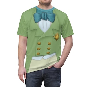 May include: A green t-shirt with a printed design of a man wearing a green suit with a white shirt, a blue bow tie, and a gold sun pin.