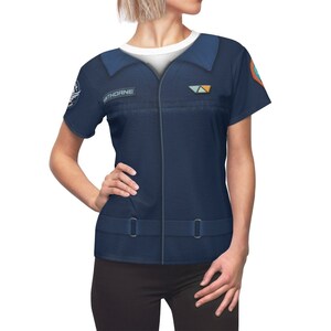 May include: A navy blue short-sleeved shirt with a zipper and a belt. The shirt has a patch with the word "THORNE" on the left side of the chest and a patch with a triangle design on the right side of the chest.