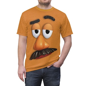 May include: A yellow t-shirt with a cartoon face printed on the front. The face has a large orange nose, black eyebrows, and a black mustache.