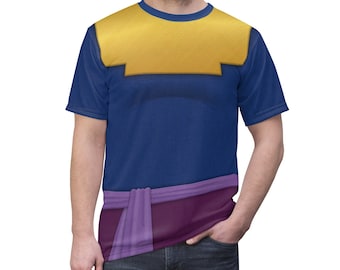 May include: A blue and purple short-sleeved t-shirt with a yellow design on the chest. The shirt has a purple sash around the waist.