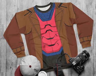 May include: A brown and red sweatshirt with a design resembling a superhero costume. The sweatshirt features a red chest piece, blue accents, and a brown jacket-like overlay. A gray baseball cap, a camera, and a coffee cup are also visible.