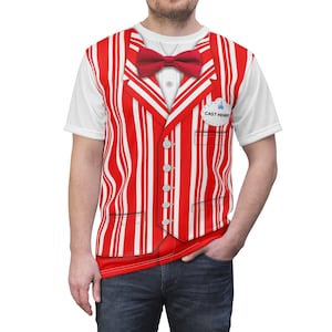 May include: A white t-shirt with a red and white striped vest printed on the front. The vest has a red bow tie and a button-up front. The shirt also has a blue name tag with the text "CAST MEMBER" printed on it.