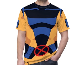 May include: A yellow, blue and black t-shirt with a stylised image of a superhero's torso. The shirt has a red X on the chest.