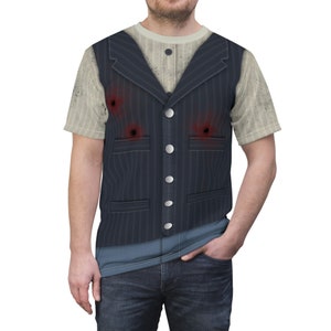 Puede incluir: Una camiseta blanca con un chaleco azul impreso en ella. El chaleco tiene un patrón de rayas finas y tres agujeros de bala. La camiseta tiene un aspecto desgastado.