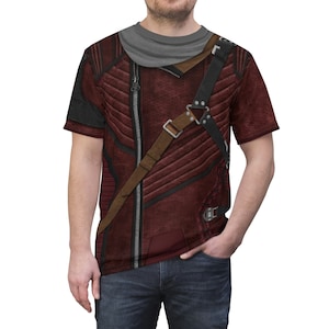 May include: A red and black short-sleeved t-shirt with a zipper and a brown strap across the chest. The shirt has a textured, distressed look.