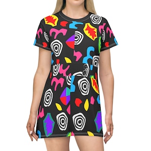Könnte beinhalten: Schwarzes Kleid mit einem lebendigen, abstrakten Muster. Das Design zeigt farbenfrohe Formen in Rot, Gelb, Blau, Rosa und Lila, die vor einem schwarzen Hintergrund abgesetzt sind. Das Kleid hat kurze Ärmel und einen runden Ausschnitt, geeignet für den Alltag.