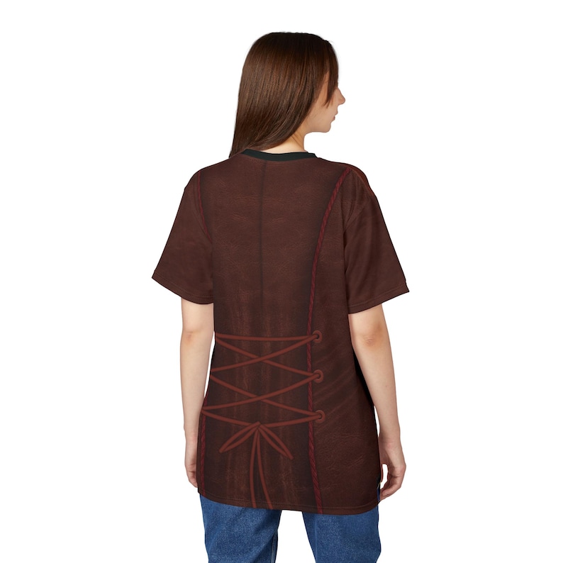 Puede incluir: Una camiseta marr&oacute;n con un dise&ntilde;o de cors&eacute; en la espalda. La camiseta presenta una textura marr&oacute;n oscuro similar al cuero con costuras y cordones rojos. El cuello es negro.