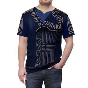 Peut inclure: T-shirt bleu marine avec une impression détaillée d'un gilet orné de motifs géométriques dorés et de boutons. Le t-shirt à manches courtes a un col rond, offrant un look unique et élégant.