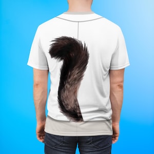 May include: White baseball-style shirt with a large, fluffy, brown and black cat tail printed on the back. The tail is curved and detailed, creating a playful and unique design. The shirt has a gray neckline and a vertical gray line down the back.