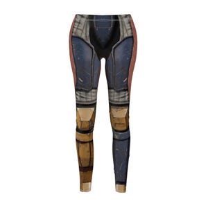 K&ouml;nnte beinhalten: Leggings mit Digitaldruck, der eine R&uuml;stung imitiert. Das Design weist Blau-, Braun- und Gelbt&ouml;ne auf, wodurch ein strukturierter, metallischer Look entsteht. Die Leggings sind eng anliegend geschnitten, mit hohem Bund und langen Beinen.