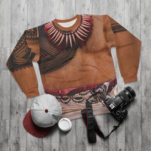 May include: A long-sleeve sweatshirt featuring a tan skin-tone base with a printed graphic of a dark tribal tattoo pattern on the chest and sleeves, a red and white tooth-style necklace design around the collar, and a red fabric waist detail.