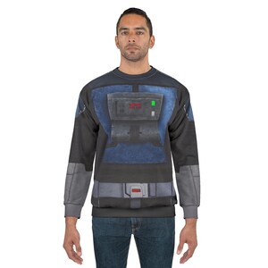 Puede incluir: Una sudadera de cuello redondo con un dise&ntilde;o de disfraz. El dise&ntilde;o presenta una placa pectoral azul y gris con detalles rojos y verdes, y detalles grises en las mangas. La sudadera la lleva una persona.