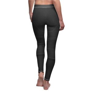 Puede incluir: Leggings negros con detalles de costuras blancas. Los leggings presentan un dise&ntilde;o con l&iacute;neas curvas y bandas horizontales. La prenda es ajustada y parece estar hecha de un material el&aacute;stico, adecuado para actividades deportivas.