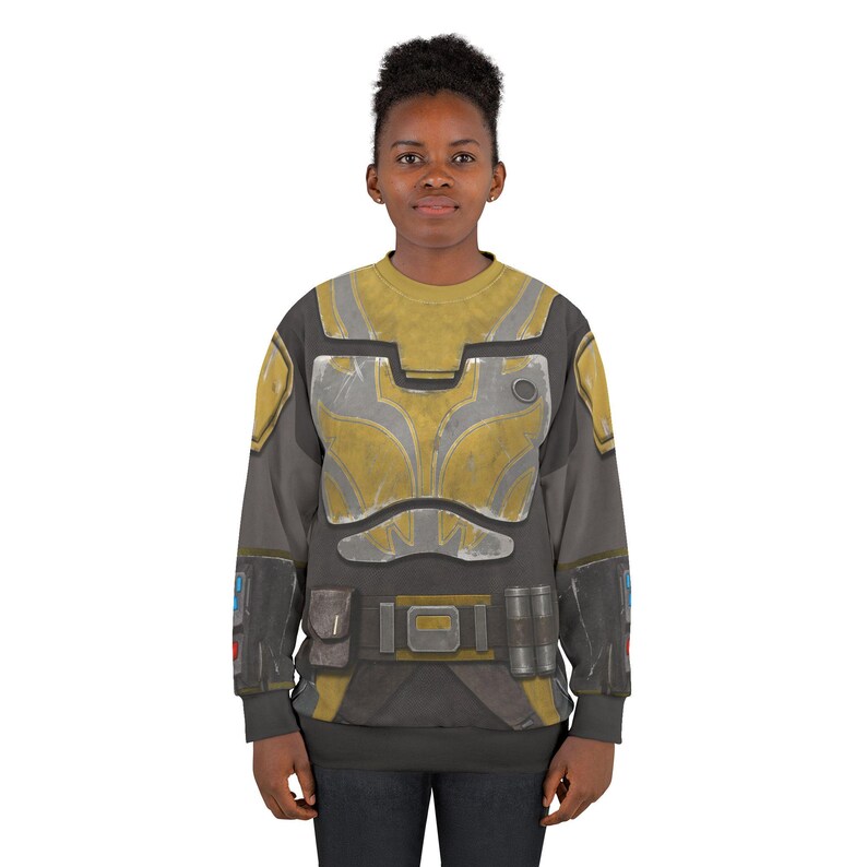 May include: A grey and yellow sweatshirt with a detailed armour design. The design incorporates yellow and silver panels, pockets, and a belt buckle. The sleeves are grey, and the overall style suggests a futuristic or sci-fi theme.