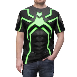Peut inclure: T-shirt noir avec un motif vert et noir. Le motif pr&eacute;sente un motif en forme d'araign&eacute;e avec des accents verts. Le t-shirt a un col rond et des manches courtes. Le t-shirt est fait d'une mati&egrave;re douce et confortable.
