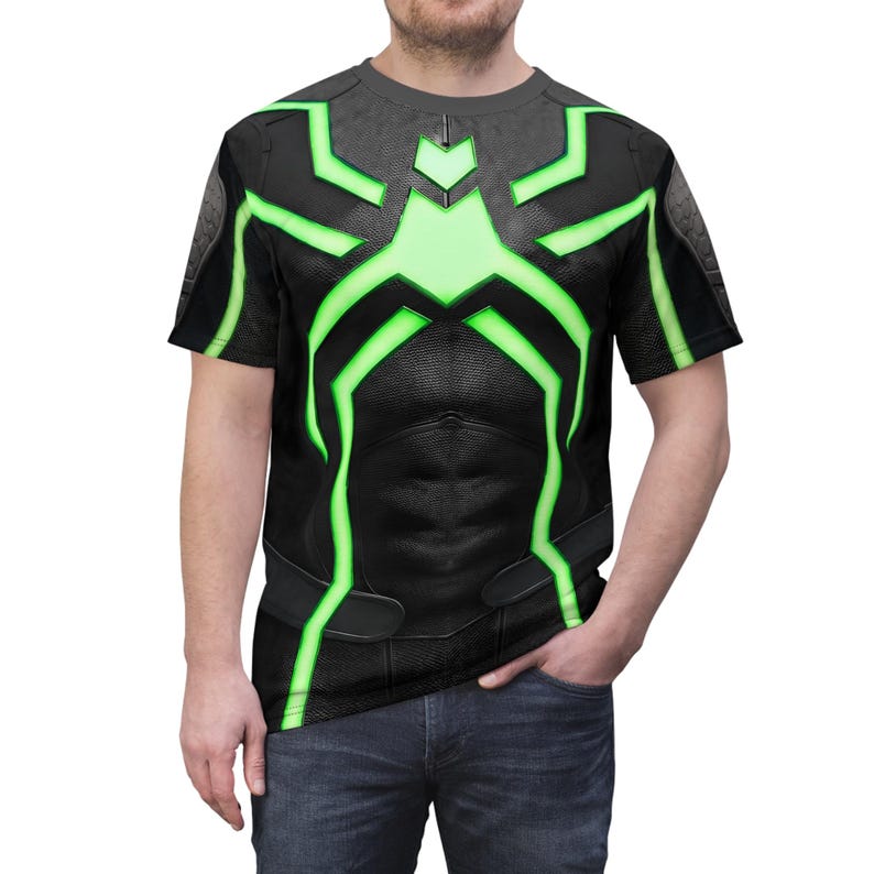 Peut inclure: T-shirt noir avec un motif vert et noir. Le motif pr&eacute;sente un motif en forme d'araign&eacute;e avec des accents verts. Le t-shirt a un col rond et des manches courtes. Le t-shirt est fait d'une mati&egrave;re douce et confortable.